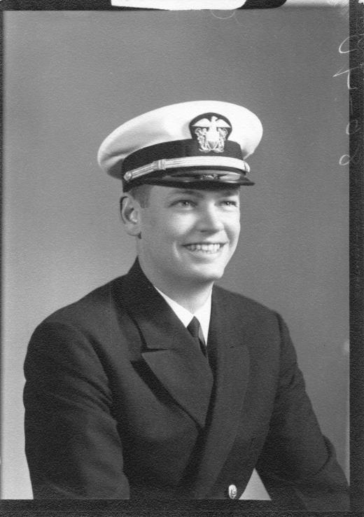 Formal portrait of Curtis as a young Navy officer in dress whites and a peaked cap, grinning broadly. 1944.